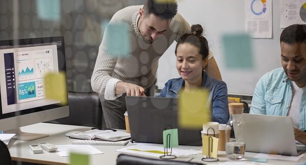 en una de las empresas de marketing, un director de marketing hace observaciones a una empleada femenina en su laptop