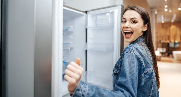 uno de los mejores refrigeradores, mujer feliz revisando un refrigerador en una tienda