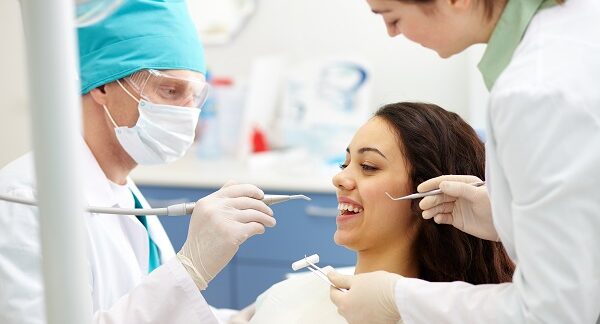 estomatólogos - uno de los mejores estomatólogos en Colombia, hace un revisión dental a paciente, con ayuda de su asistente