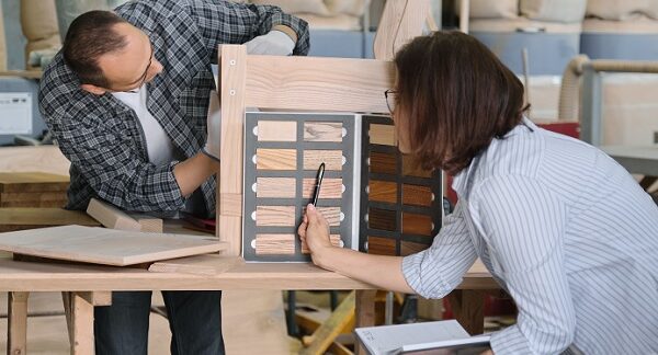 tiendas de muebles a medida, un carpintero ensambla un mueble, mientras una mujer elige colores