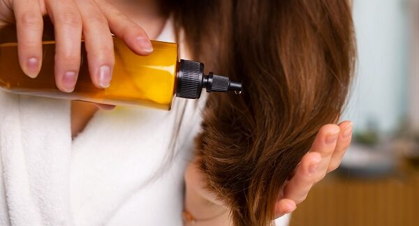 mejores aceites capilares - una mujer aplicando aceite en el cabello